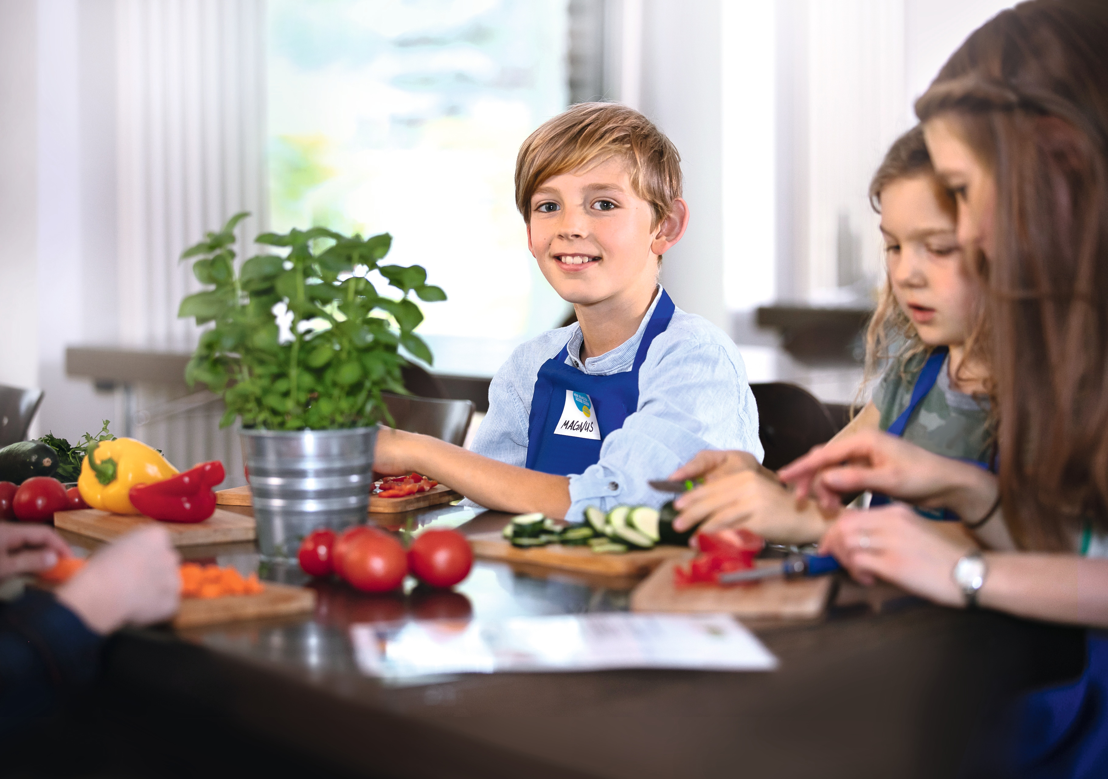 Kinder sind dabei Gemüse für das gemeinsame Mittagessen zu schneiden bei "Mehr bewegen - besser essen" der EDEKA Stiftung.