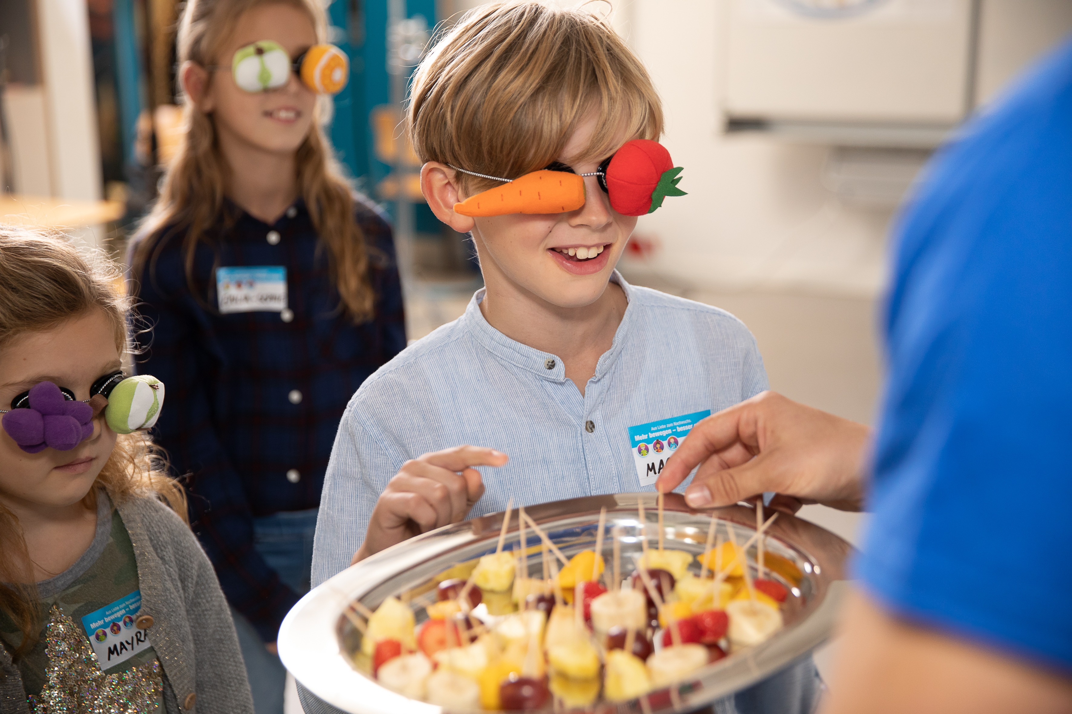 Kinder stehen mit verbundenen Augen für den Sinnensparcour am Projekttag "Mehr bewegen - besser essen" der EDEKA Stiftung an.